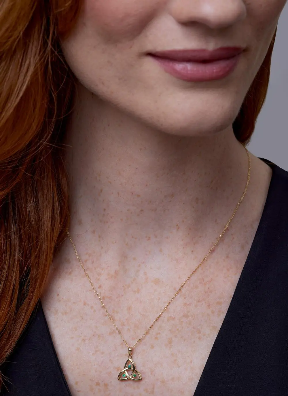Close up shot of red haired model wearing 14ct Gold Emerald Trinity Knot Pendant