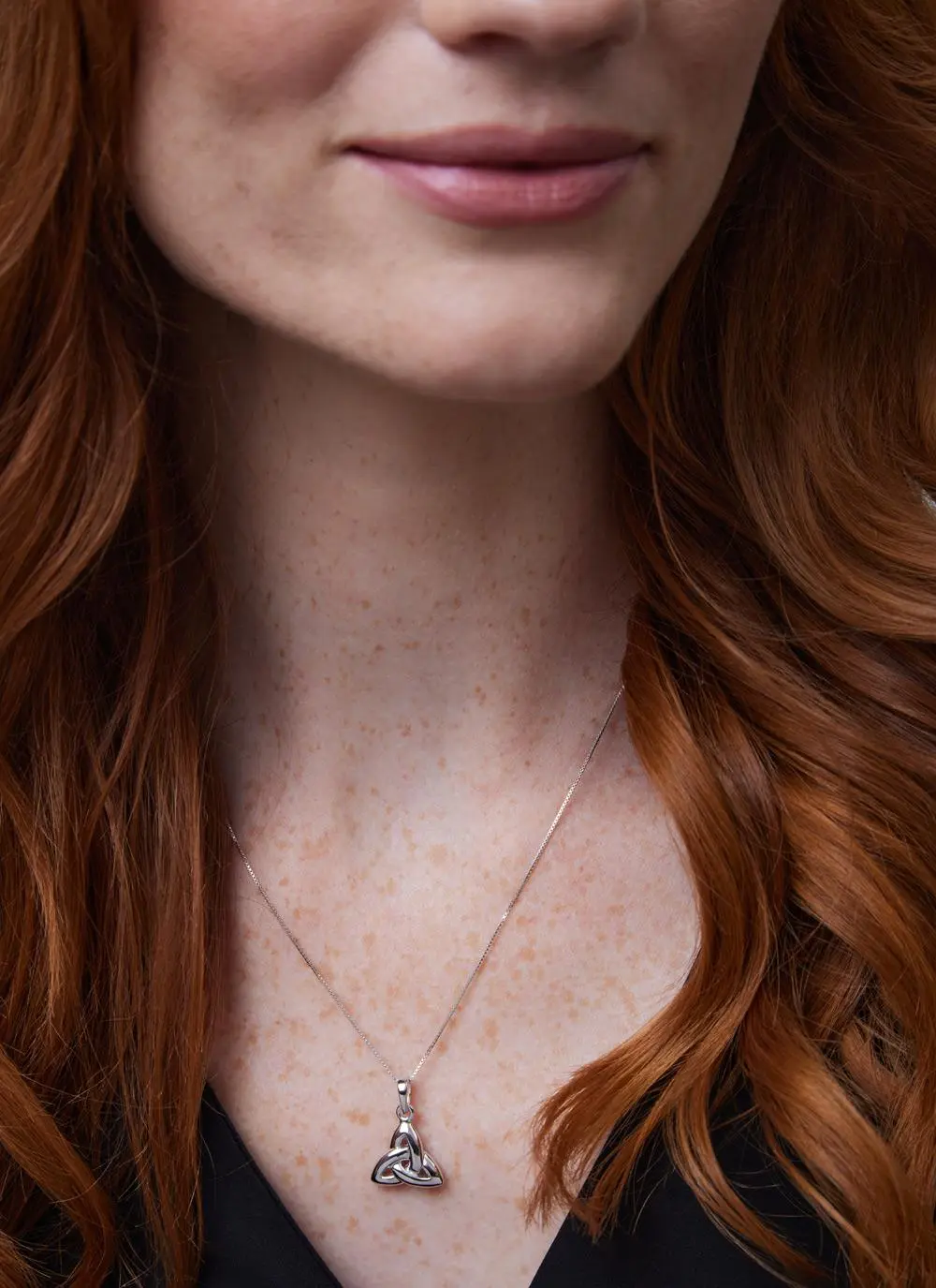Close up shot of red haired woman wearing Sterling Silver Double Sided Trinity Knot Pendant