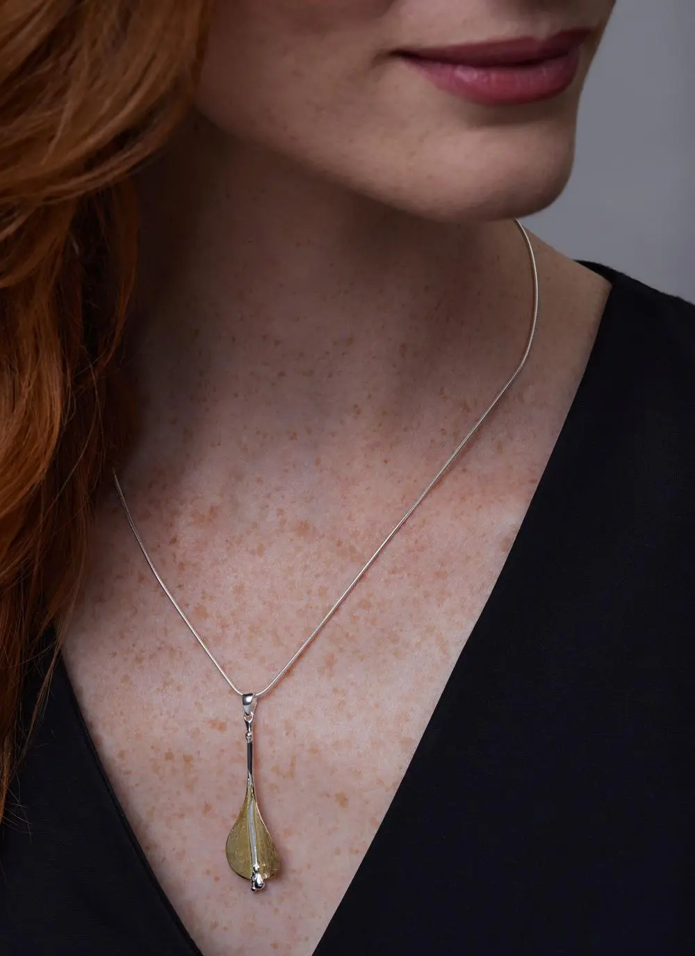 Close up of red haired model wearing Two Tone Lily Pendant with matching earrings